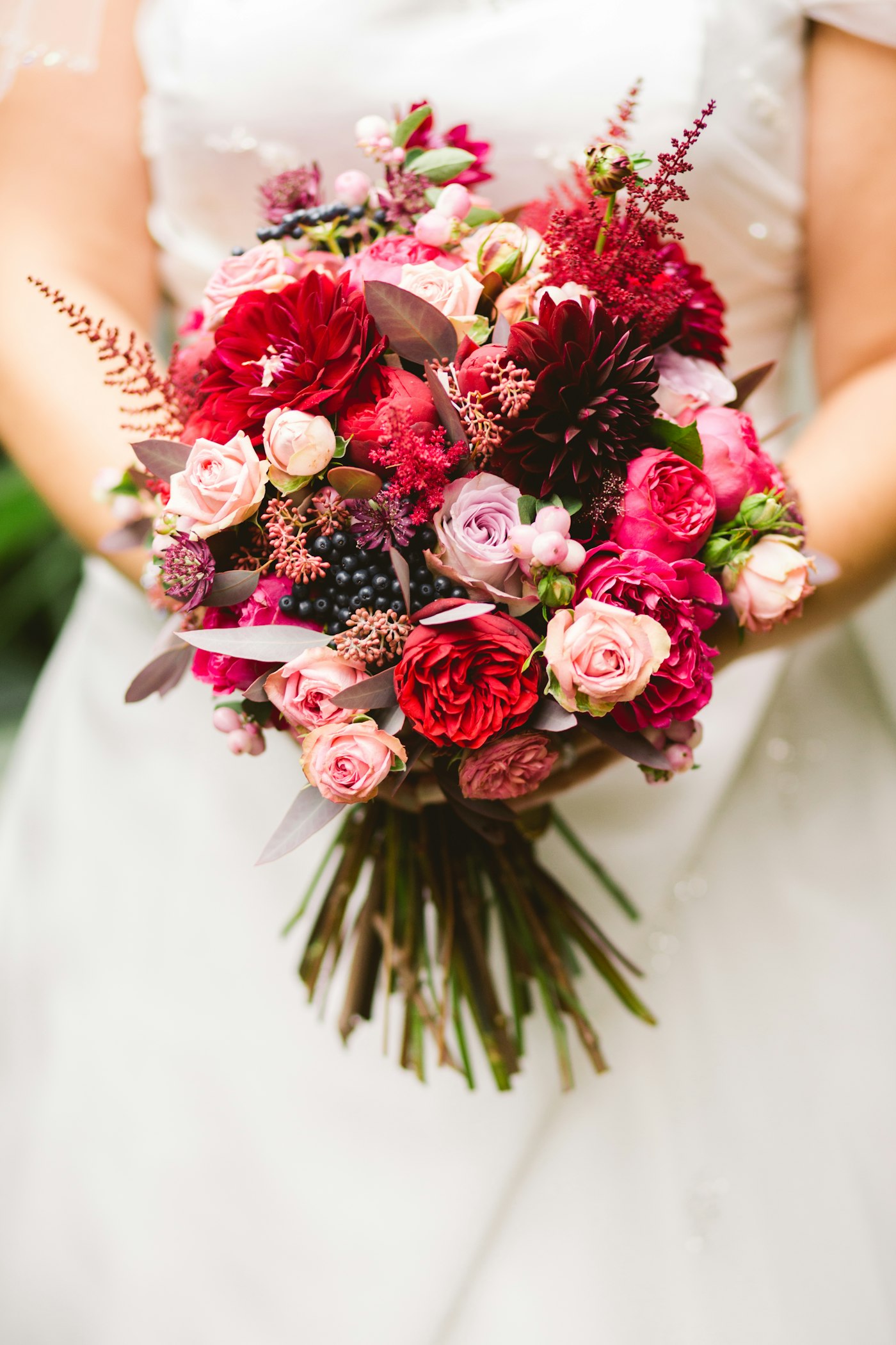 Brud som holder en vakker brudebukett med friske blomster